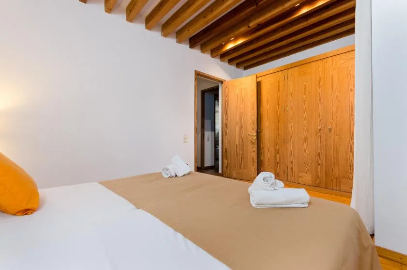 Un dormitorio con camas, armarios de madera y vigas expuestas en el techo.