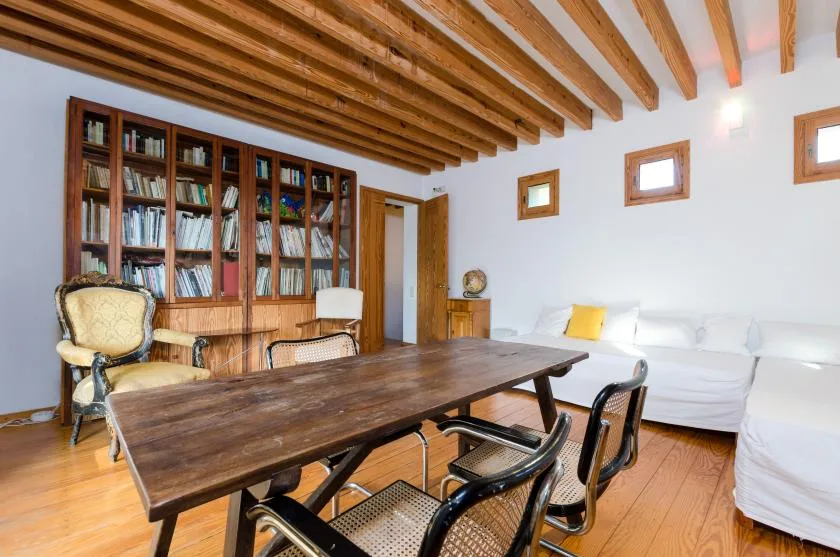 Comedor con una mesa larga de madera y una estantería junto a la pared.