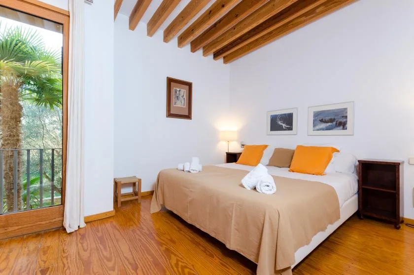 Un dormitorio con una cama grande, mesitas de noche y vigas de techo expuestas.