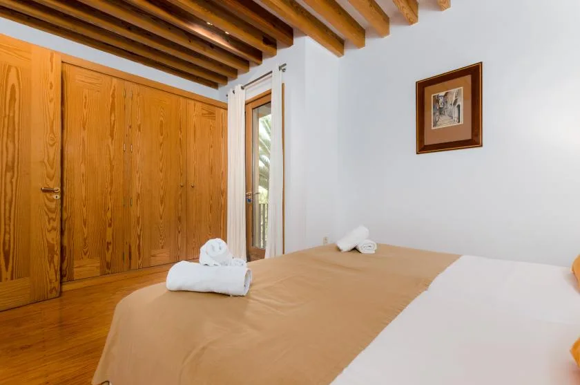 Un dormitorio con una cama, armarios de madera y vigas vistas en el techo.