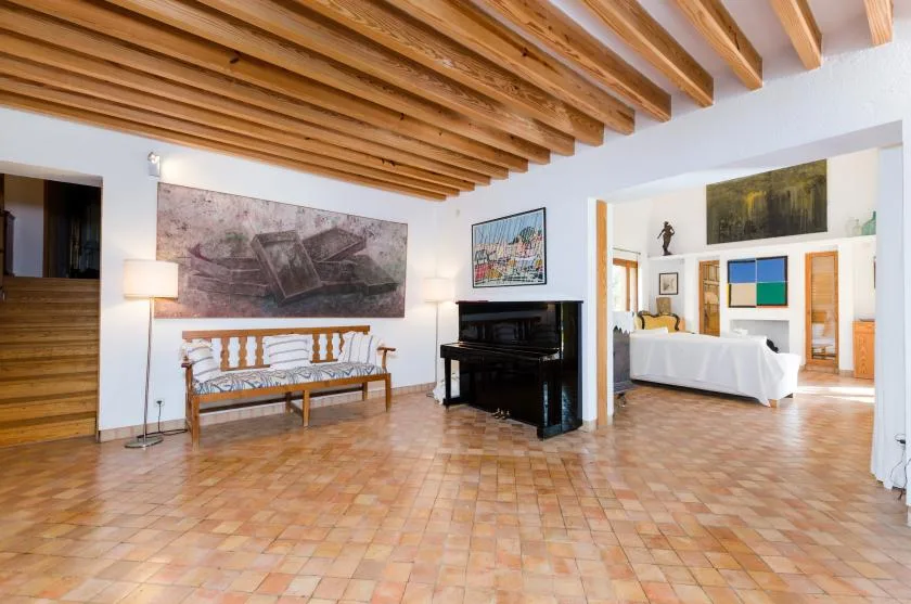 Un interior amplio con techo de vigas de madera y un piano junto a la zona de estar.