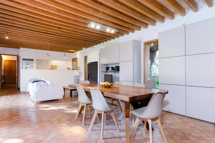 Un espacio abierto de comedor y sala de estar con una mesa larga de madera y asientos.