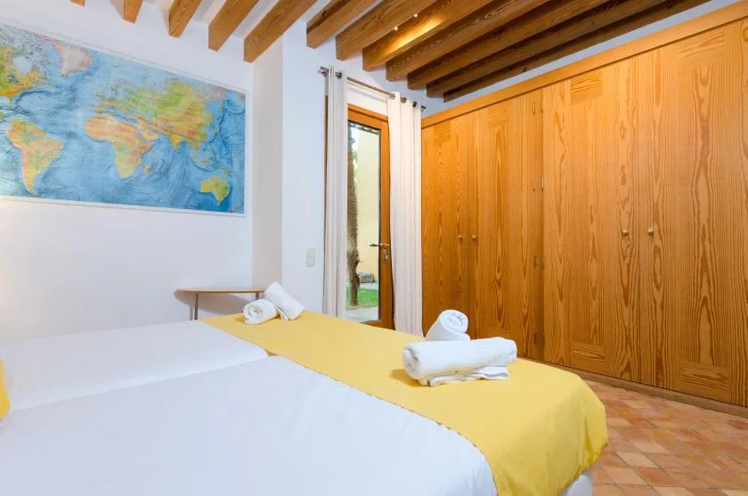 Un dormitorio con camas, ropa de cama amarilla y armarios de madera.