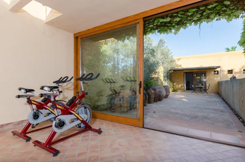 Un patio embaldosado con bicicletas estáticas junto a una gran puerta corrediza de vidrio.