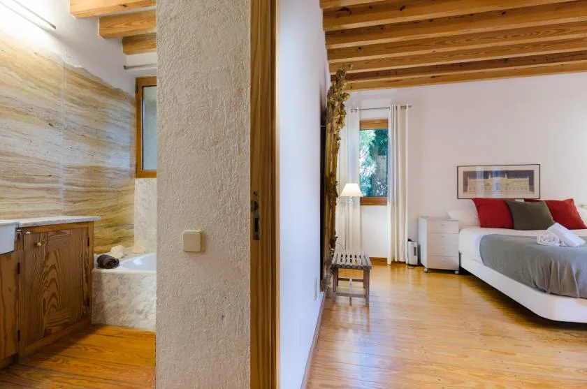 Un dormitorio con una cama y un baño contiguo parcialmente visible.