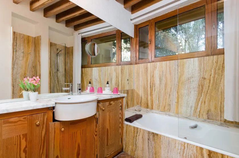 Un baño con lavabo, bañera y ventanas con marcos de madera.