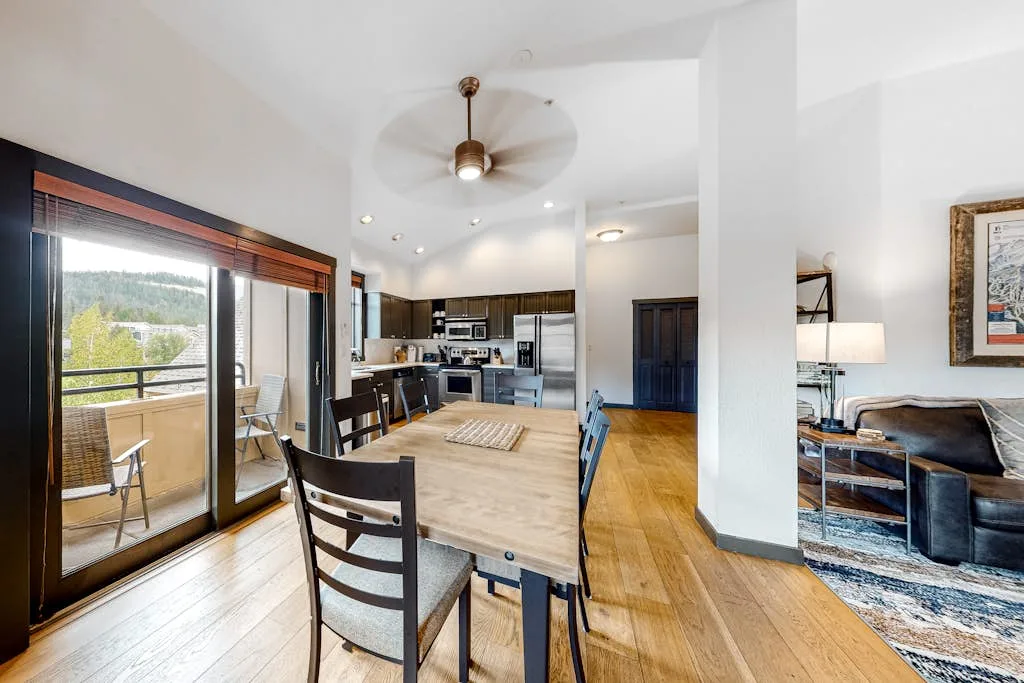 An open-plan dining and living area with a wooden table beside the kitchen.
