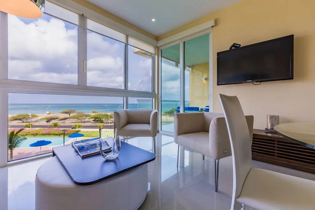Relax in your stylish living area with floor-to-ceiling windows framing stunning sea and coastal views. Settle into modern seating with your morning coffee or unwind as the ocean breeze drifts through.