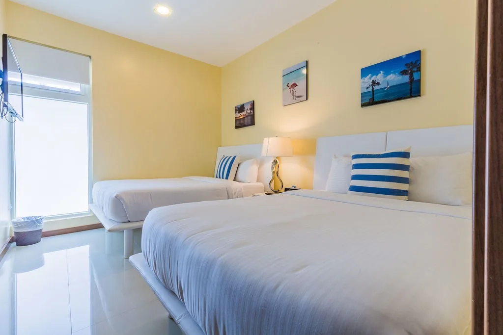 Your coastal-themed bedroom features two plush beds with crisp linens and cheerful striped pillows, perfect for restful nights after beach adventures.