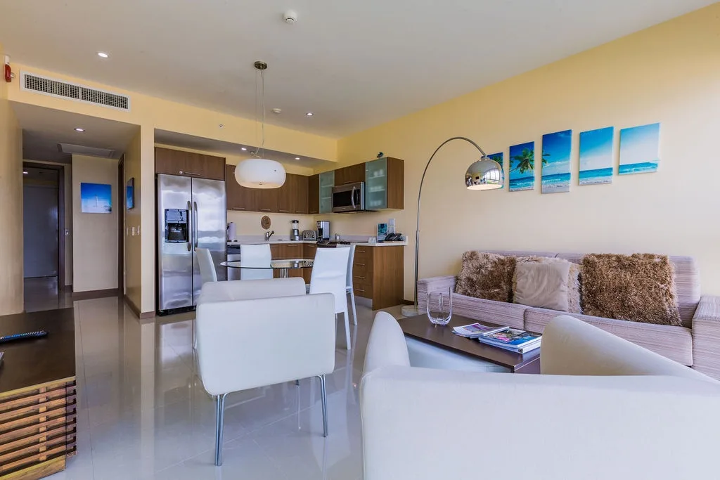 Relax in your bright, modern open-plan space with a fully equipped kitchen, stylish dining area, and cozy seating—your perfect tropical escape awaits.
