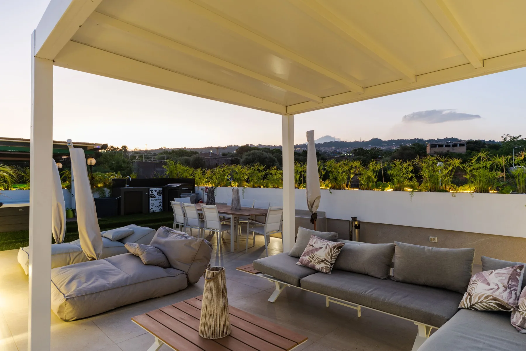 A covered outdoor seating area overlooks greenery and distant hills.
