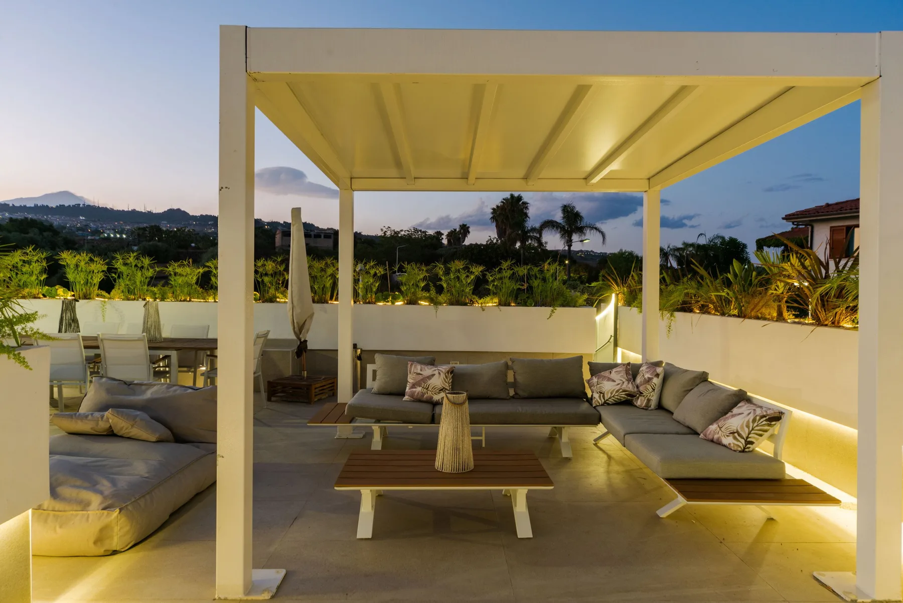 A covered outdoor seating area with cushioned seating and a low table.