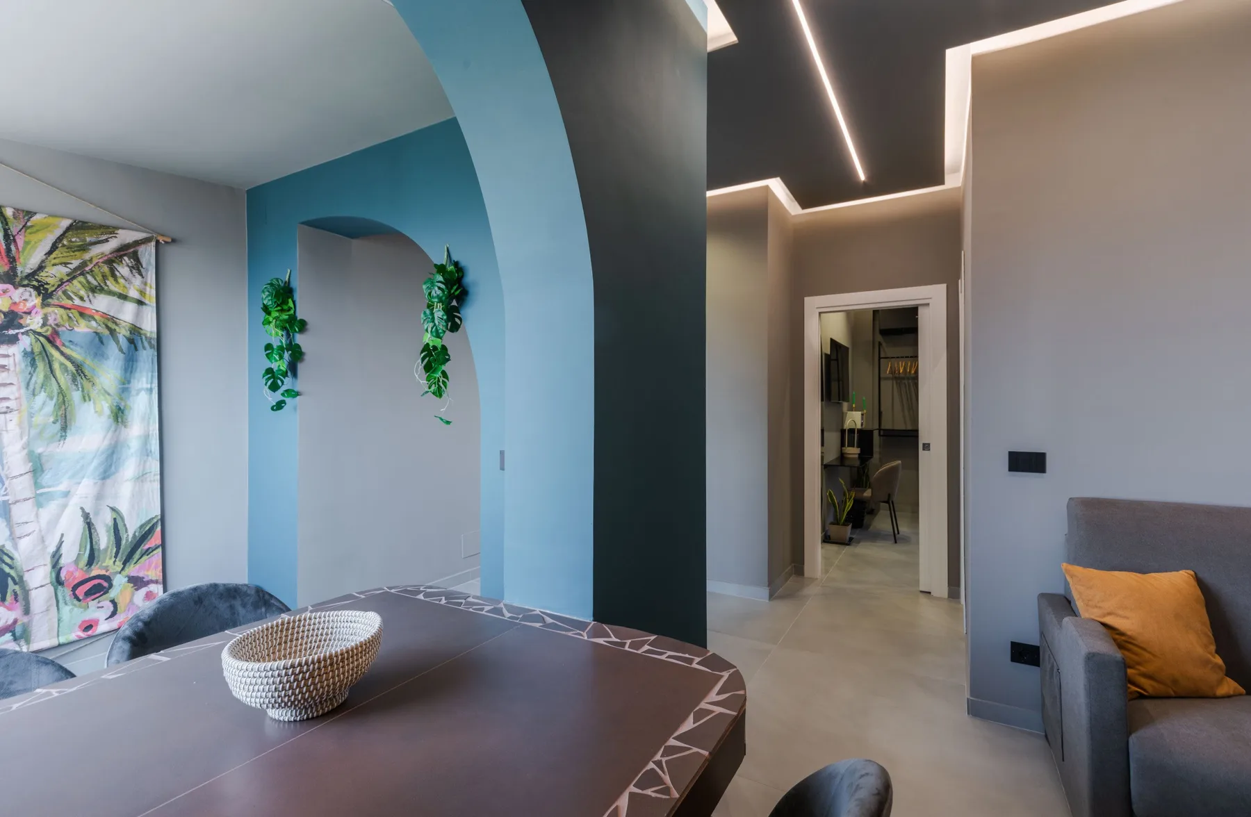 A modern living room with a dining table and colorful wall art.