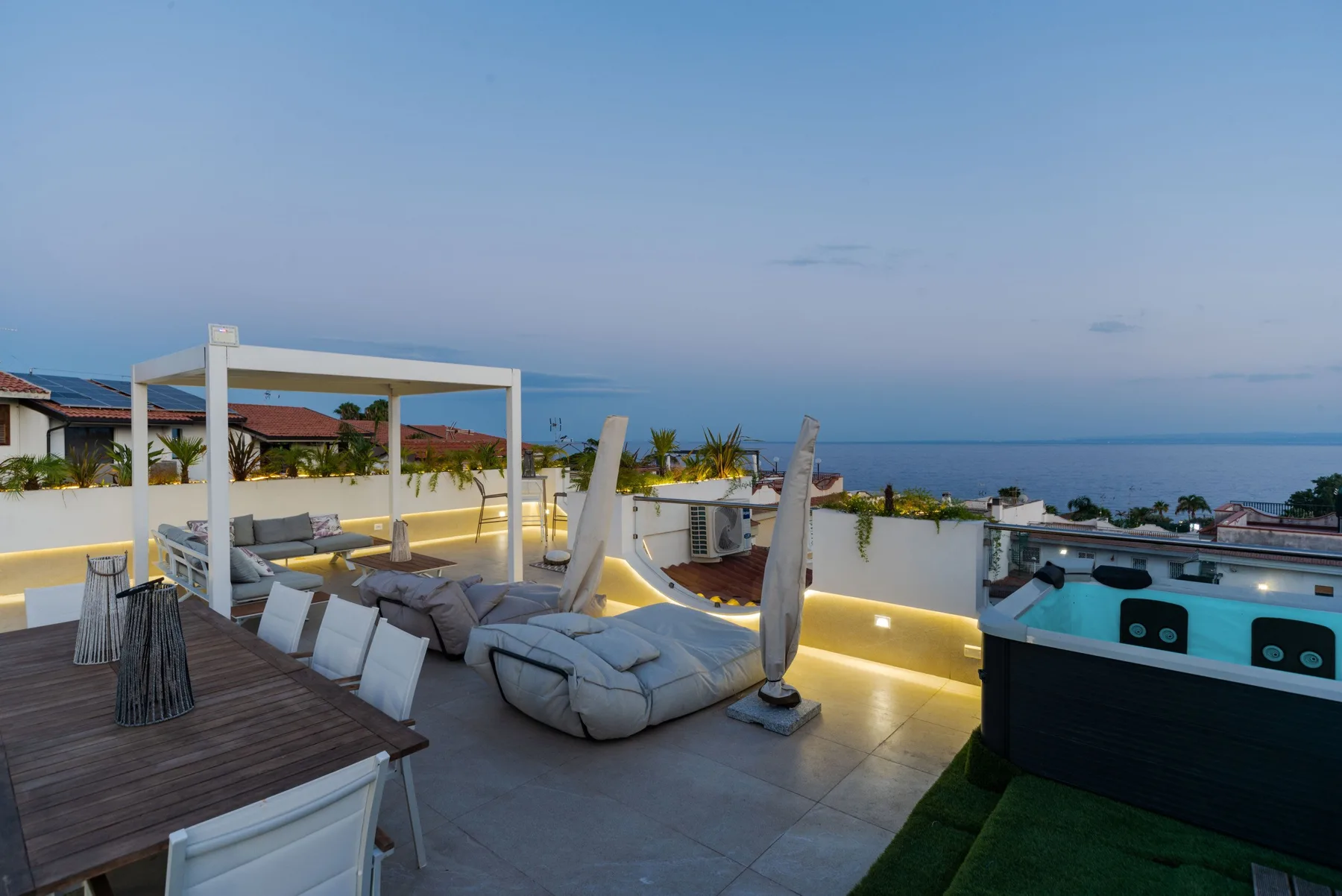 A rooftop terrace with lounge seating and a hot tub overlooks the ocean.