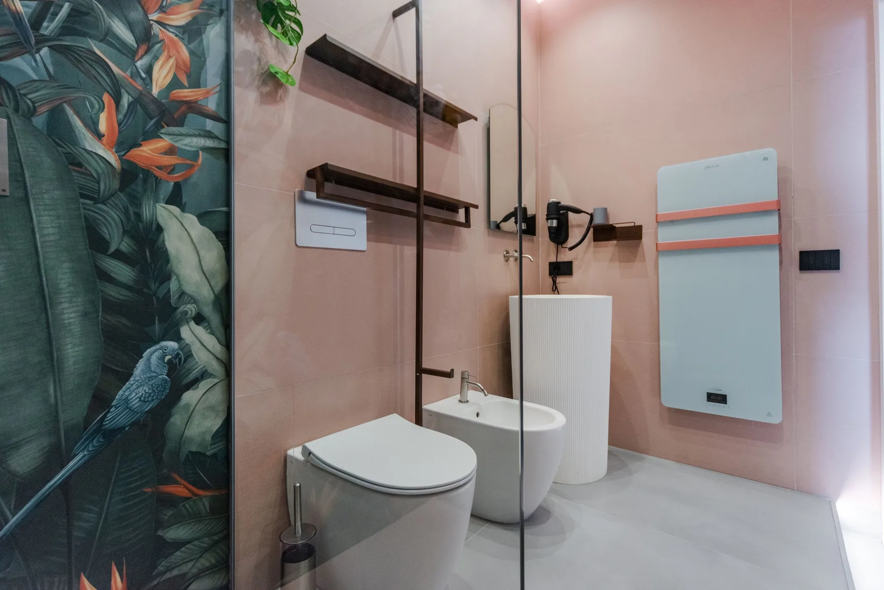 A modern bathroom with a toilet, sink, and glass shower screen.