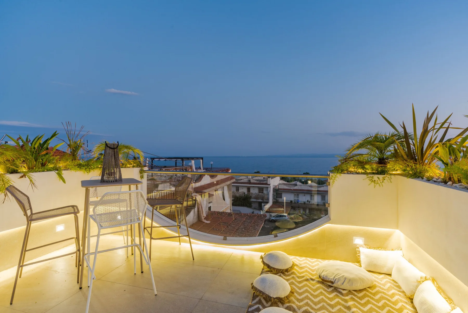 A rooftop terrace with seating and a cushioned lounge area overlooking the sea.
