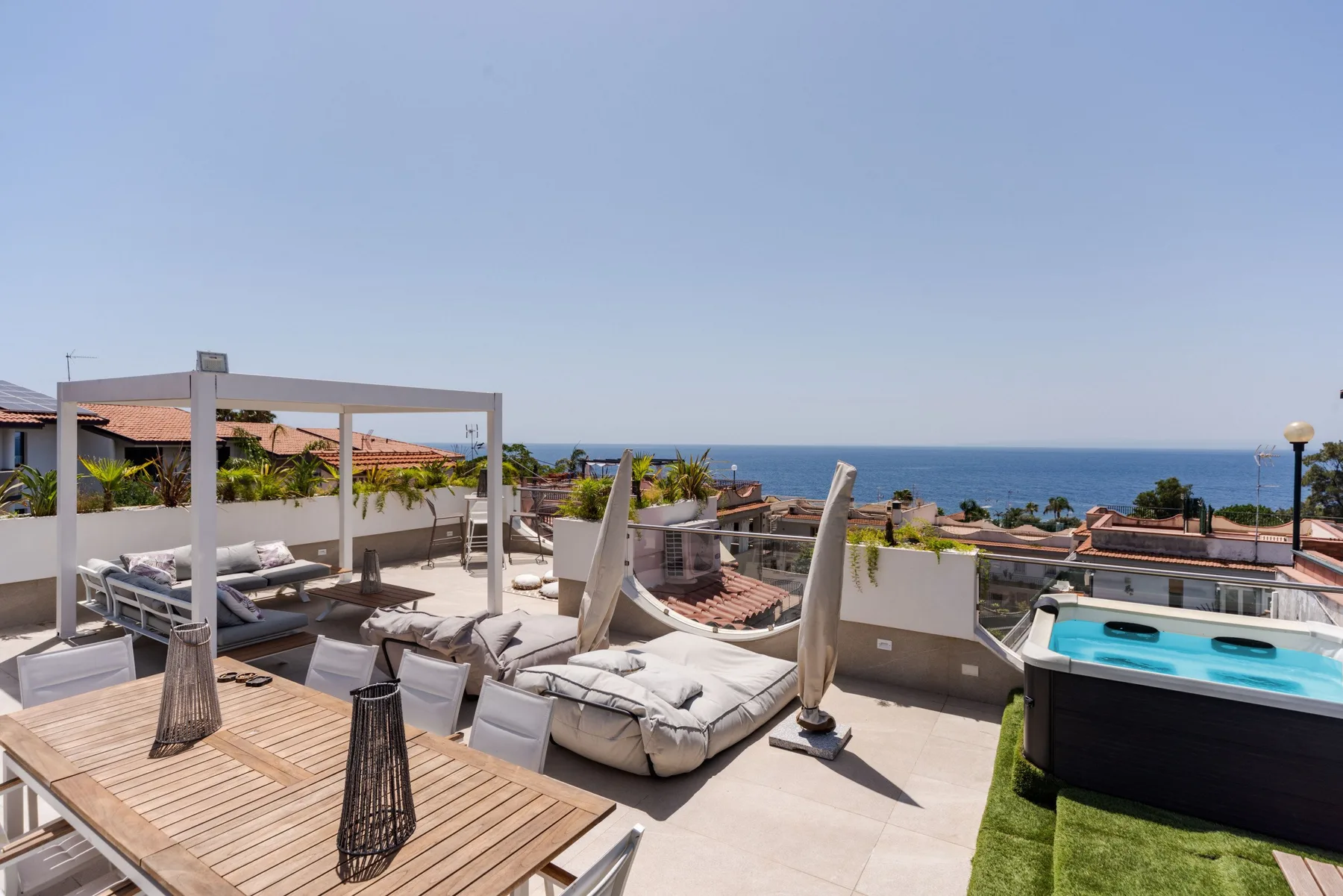 A rooftop terrace with outdoor seating and a hot tub overlooking the sea.