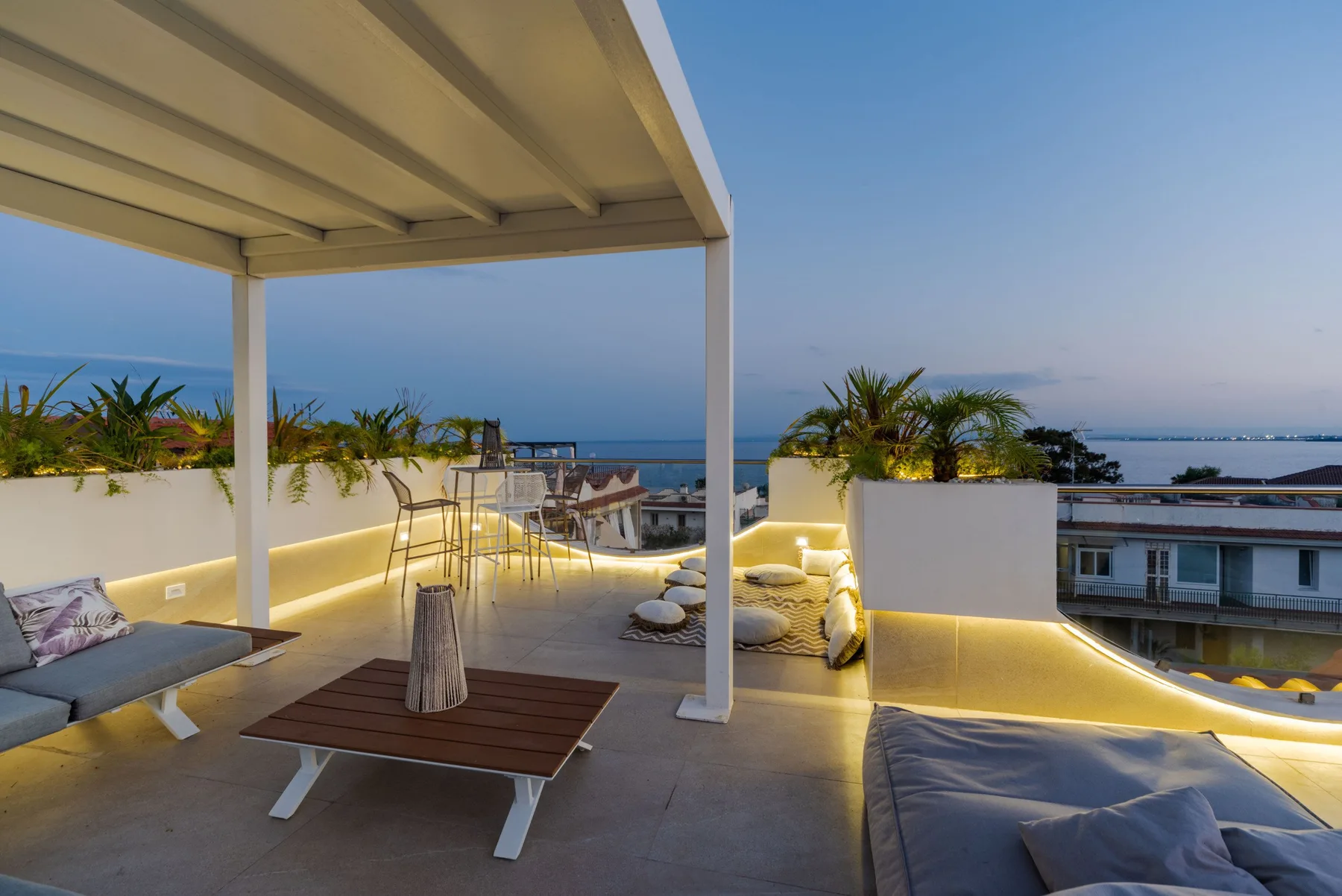 An outdoor rooftop terrace with lounge seating and a view of the sea.