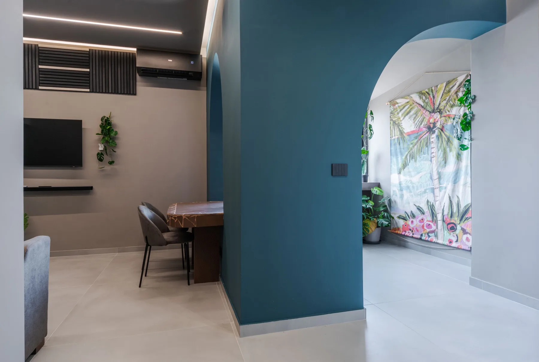 A modern living and dining area with a teal partition and a patterned curtain.