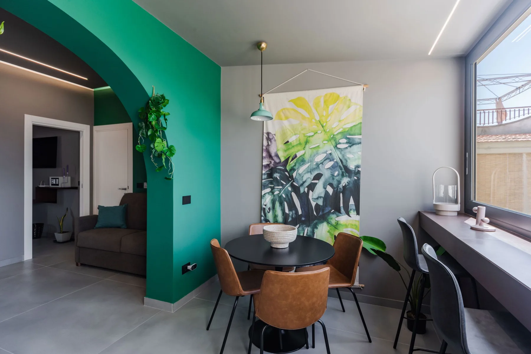 A modern dining and seating area with a round table beneath colorful wall art.