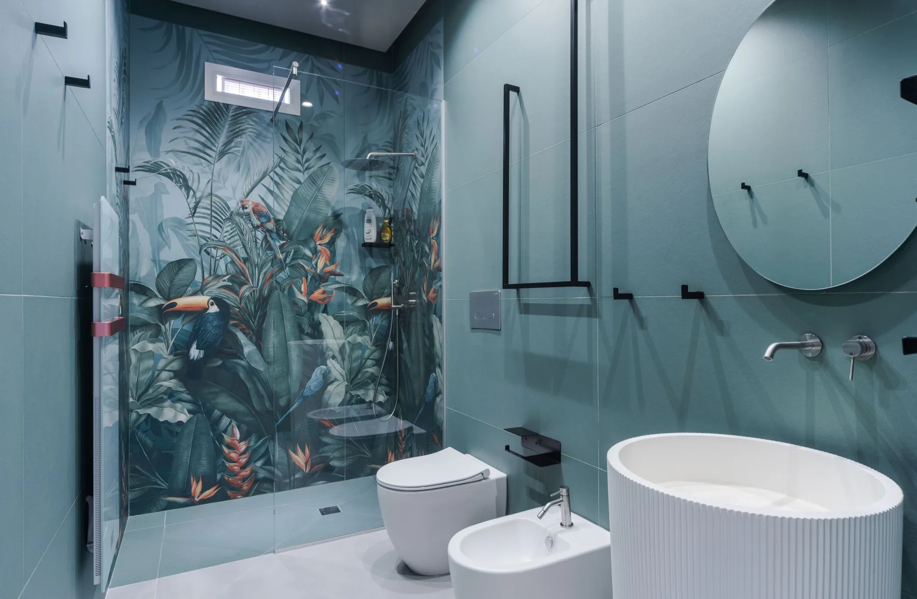 A modern bathroom with a freestanding tub and a tropical-patterned shower wall.