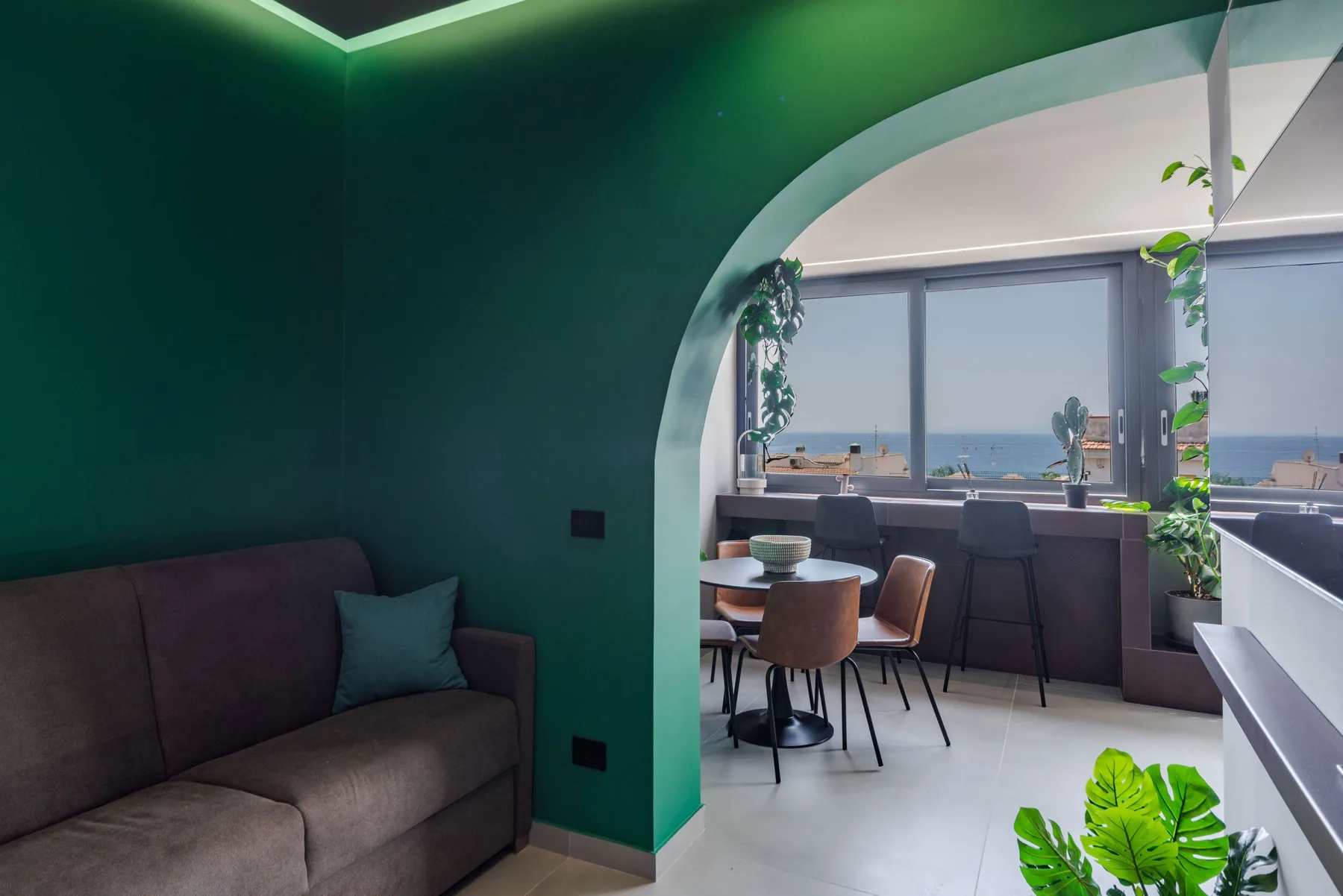 A dining area opens onto a counter and large windows overlooking the sea.