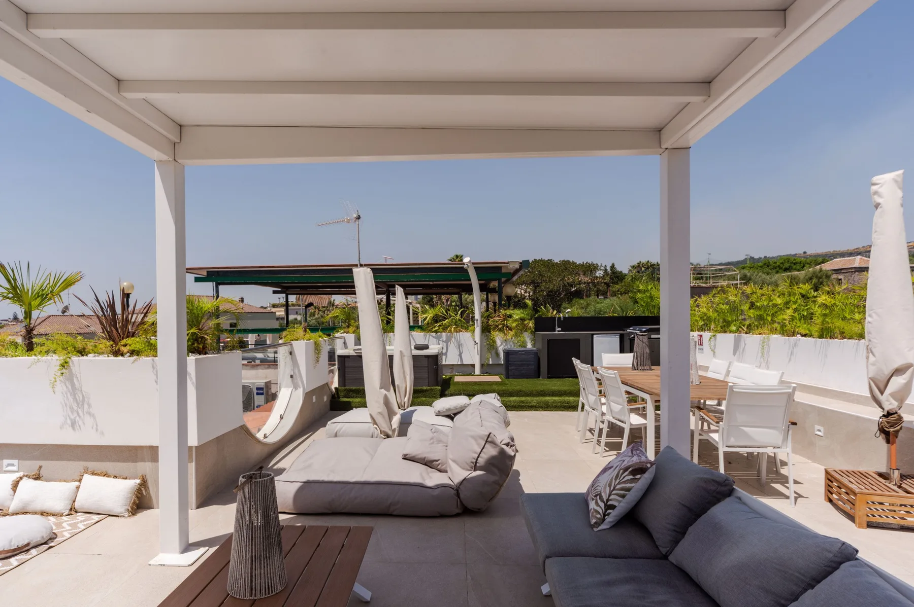 A covered outdoor terrace with cushioned seating and a dining area.
