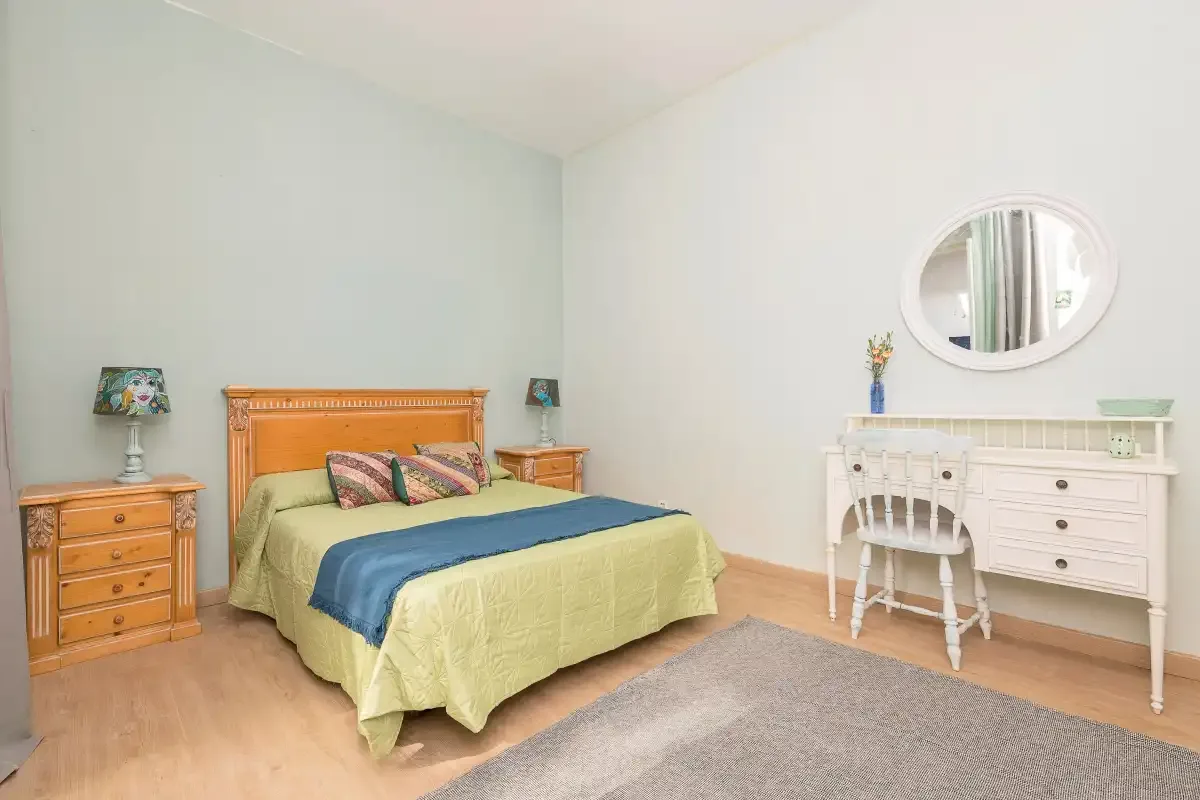 A bedroom with a bed, bedside tables, and a white dresser.