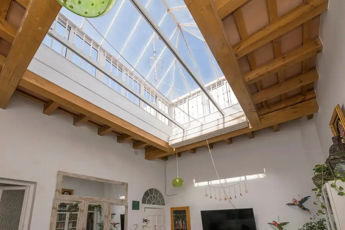 Interior room with a large glass skylight beneath exposed wooden beams.