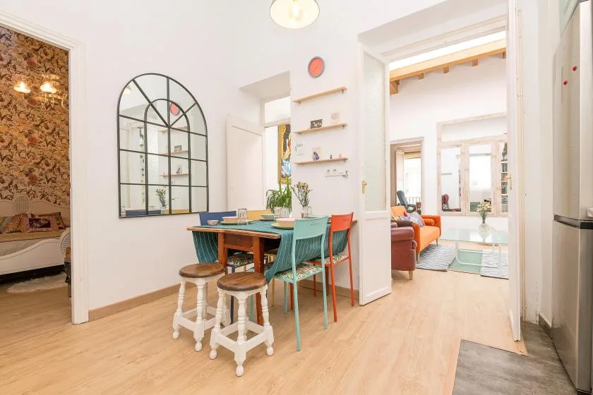 A dining area with a table and chairs sits beside an open doorway to a living space.