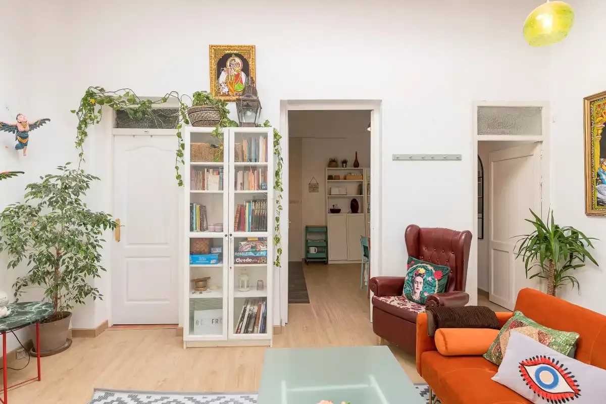 A bright living room with colorful seating, plants, and a glass coffee table.