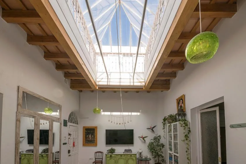 A bright living room with a television beneath a glass skylight.