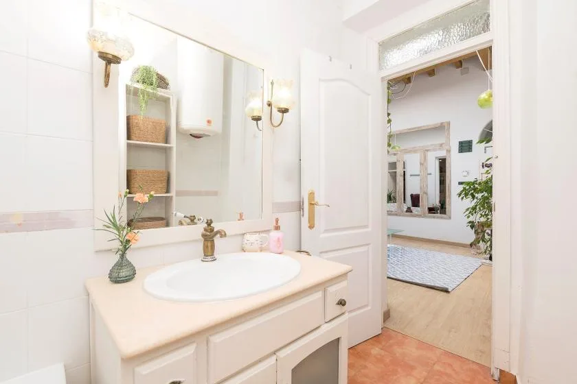 A bright bathroom with a sink and an open doorway into the adjoining room.