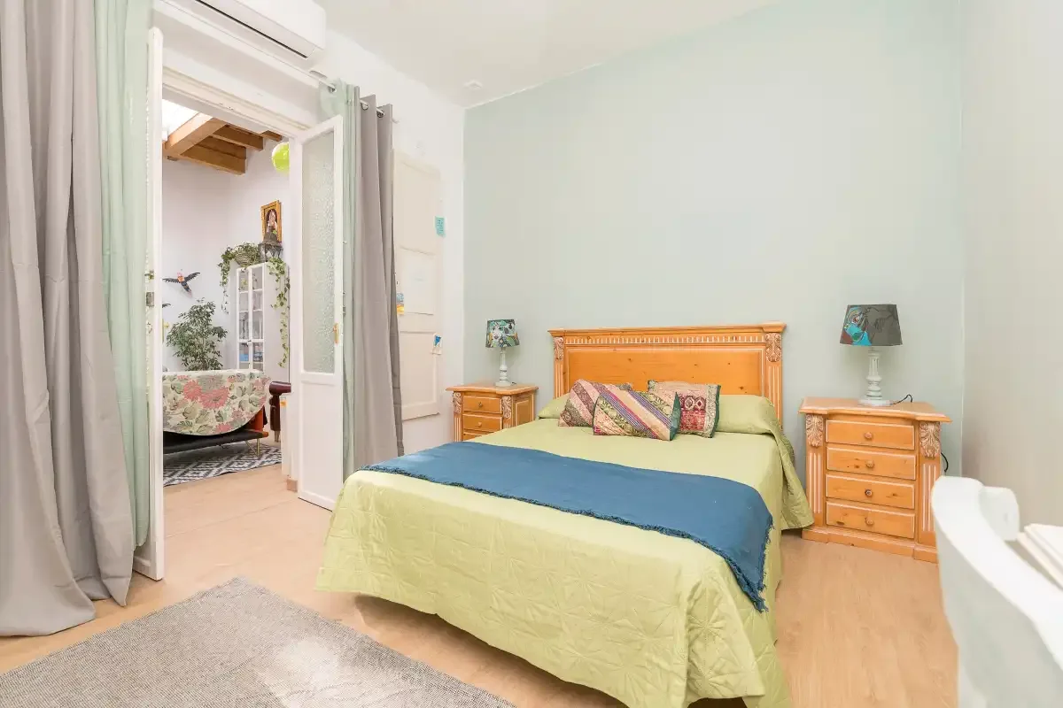 A bedroom with a bed, bedside tables, and an open doorway.