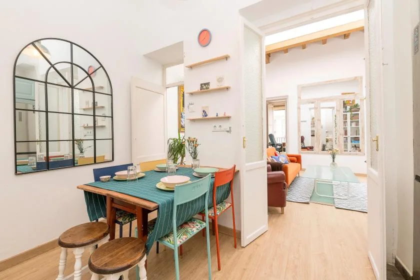 A dining area with a teal table beside an open doorway to a living room.