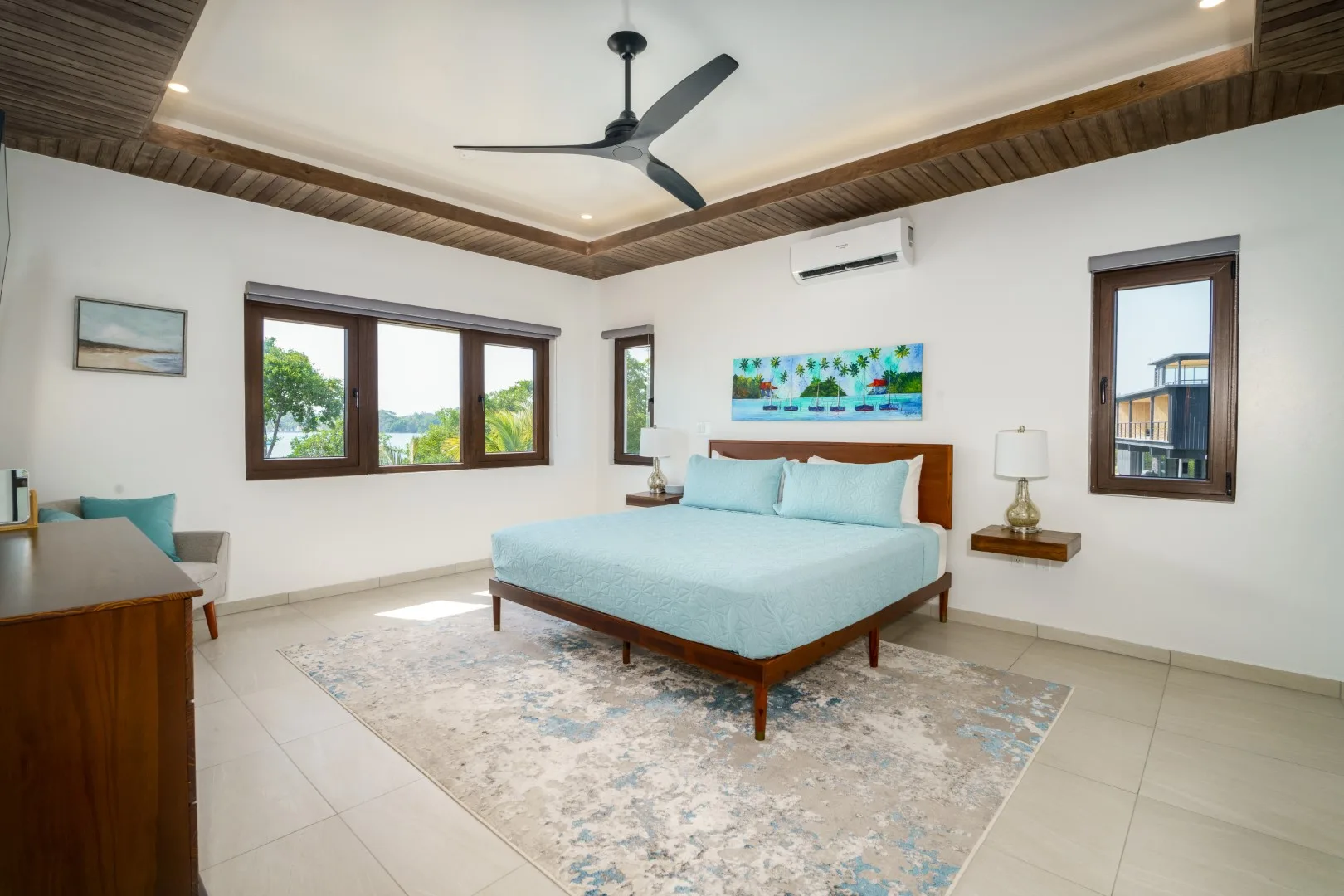 A bright bedroom with a bed beneath a ceiling fan.