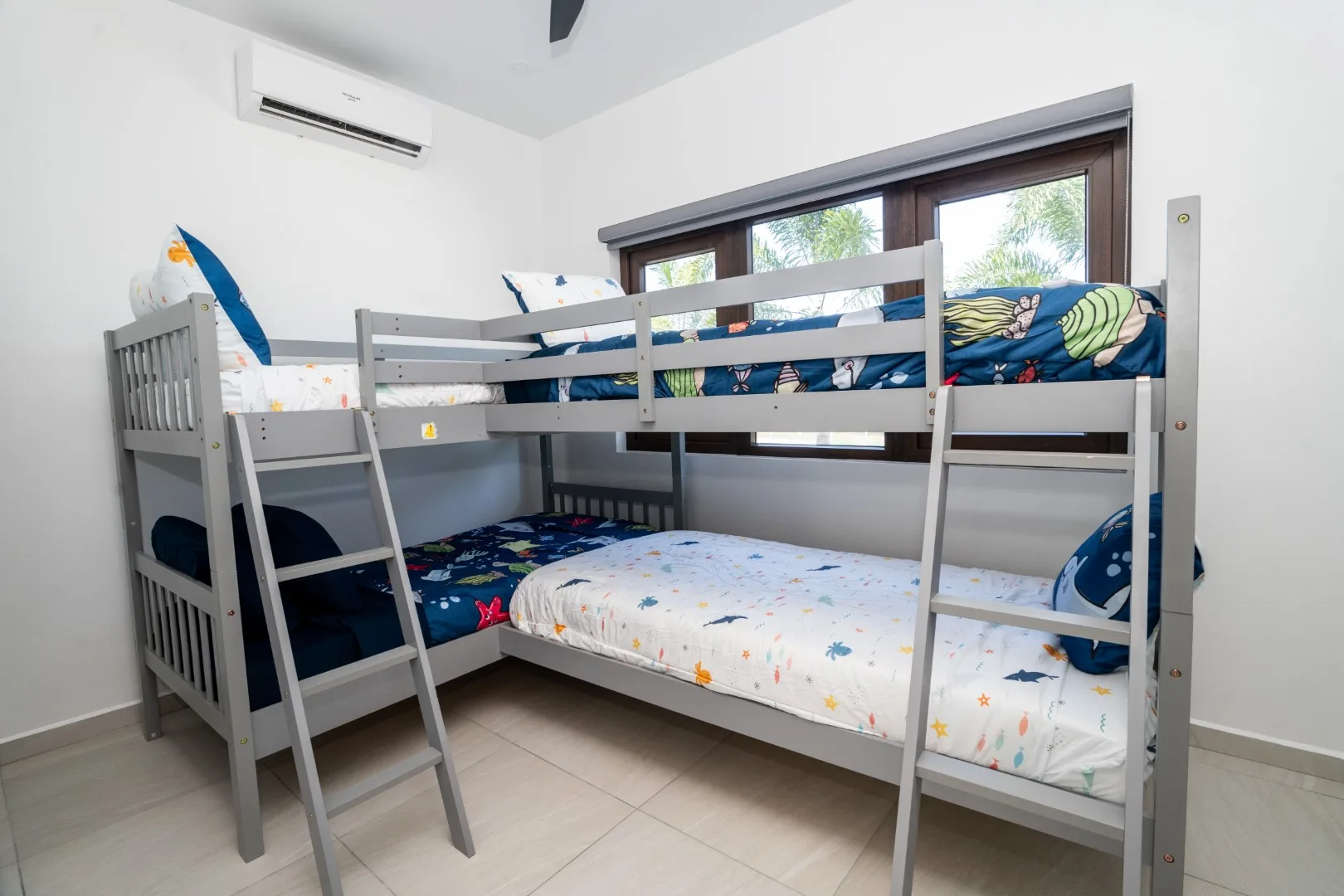 A bunk bed with colorful bedding sits beneath a wide window.