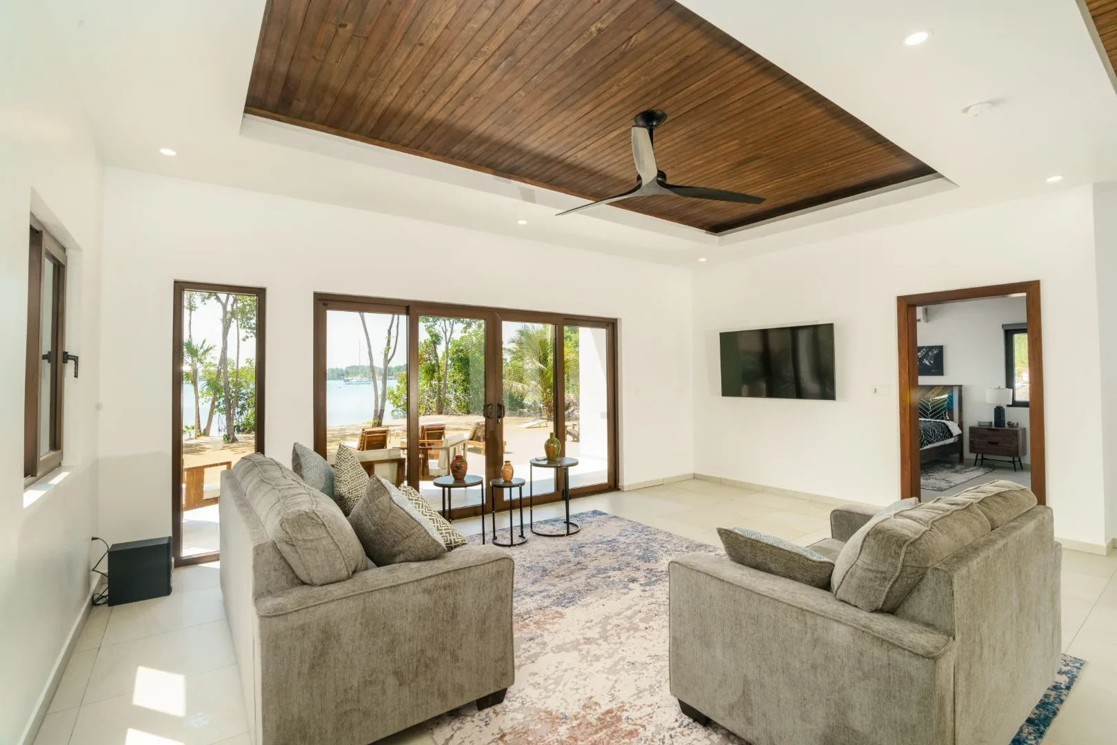 A bright living room with seating, a television, and glass doors opening to a patio.