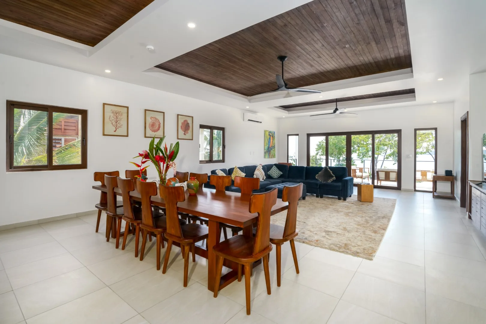 A dining and living area with a long wooden table and dark seating.