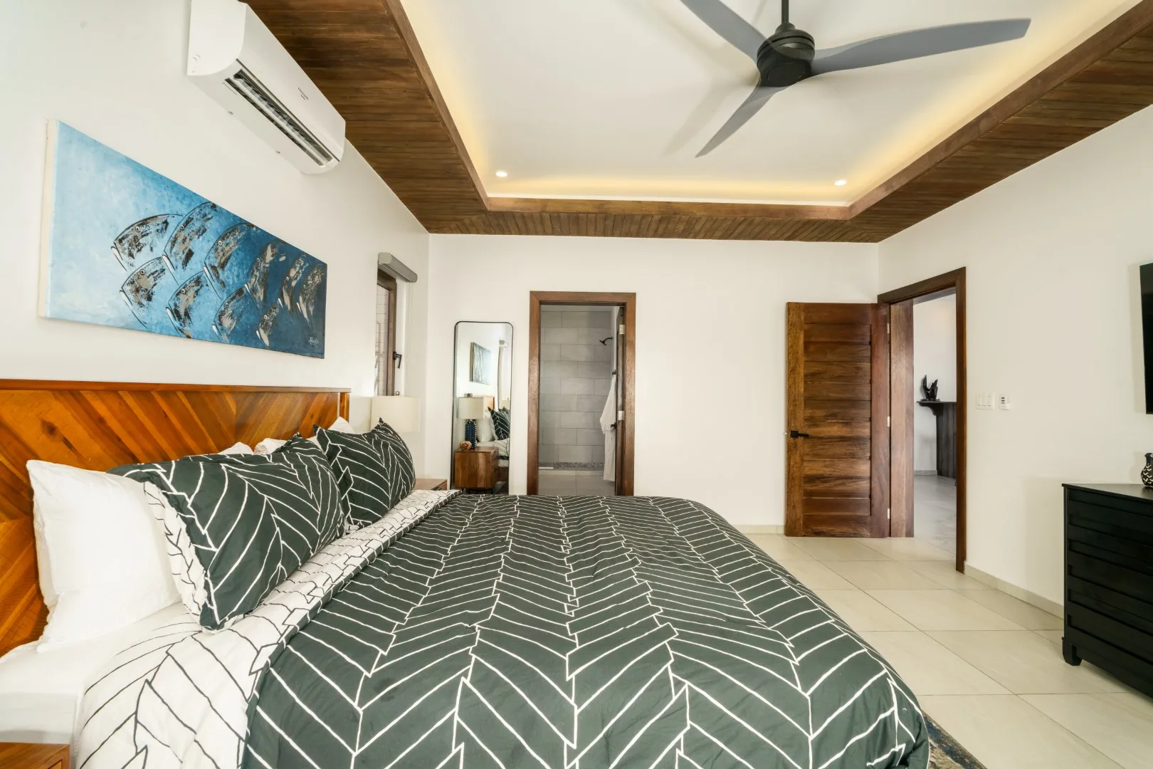 A bedroom with a large bed, patterned bedding, and wooden doors.