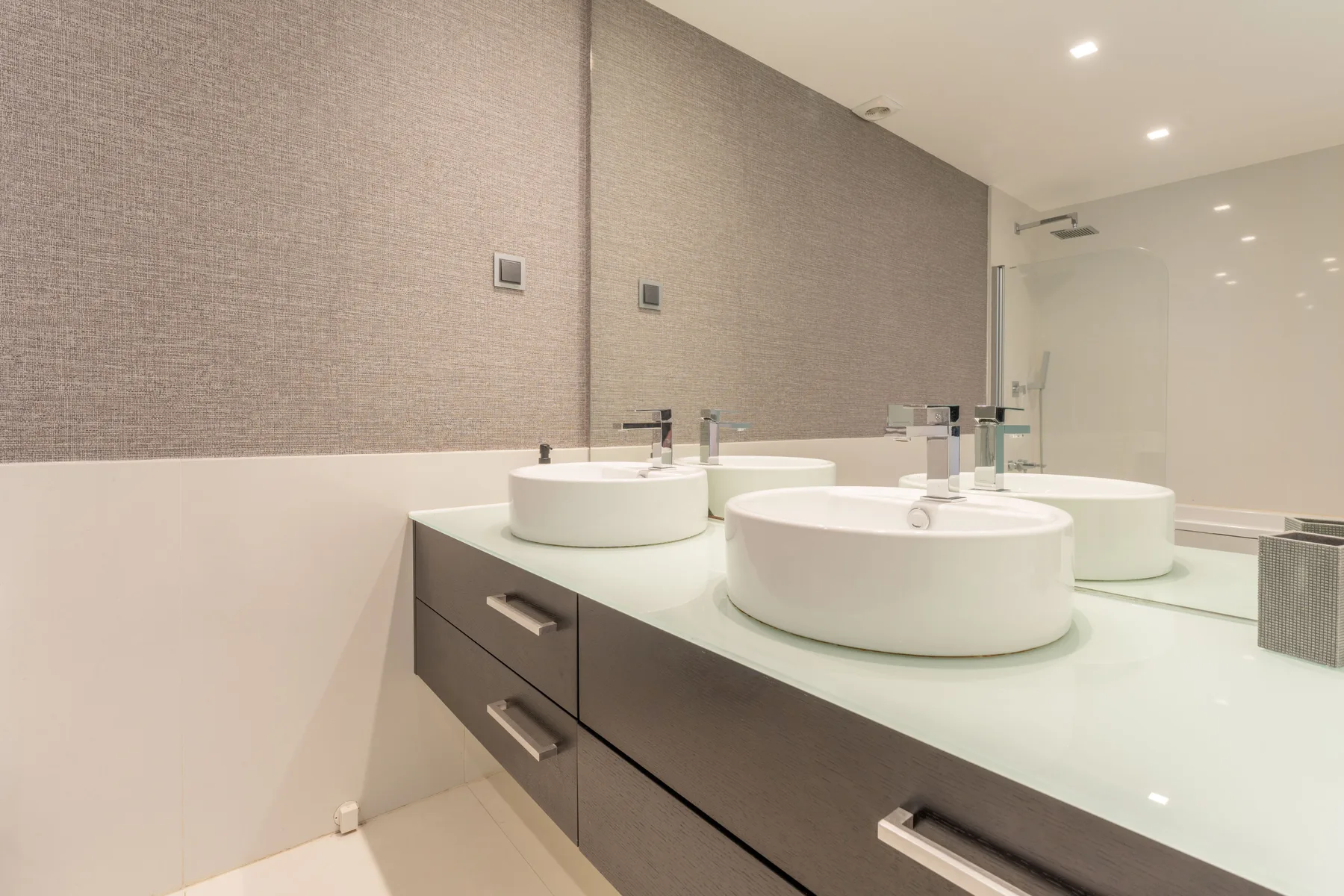 Un baño luminoso con un tocador largo y varios lavabos.