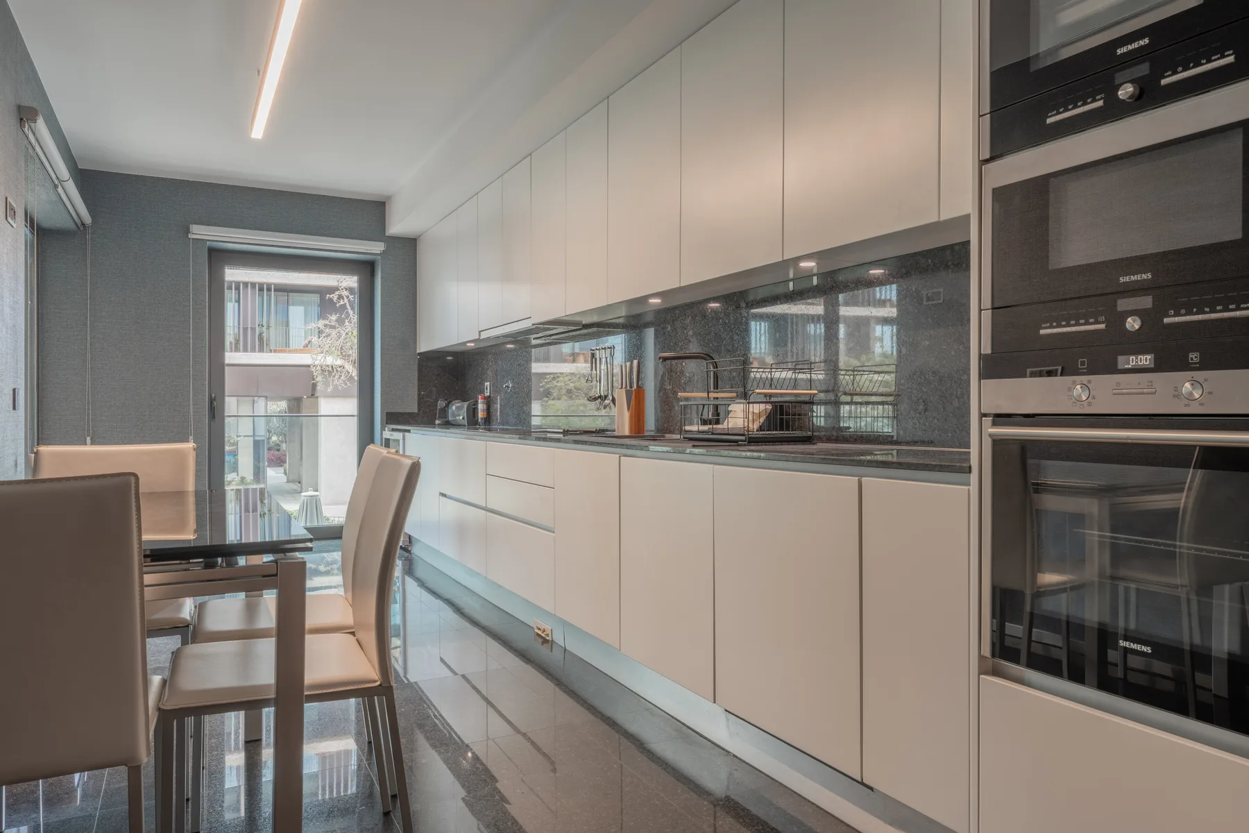 Una cocina moderna con una mesa de comedor junto a una puerta de vidrio.