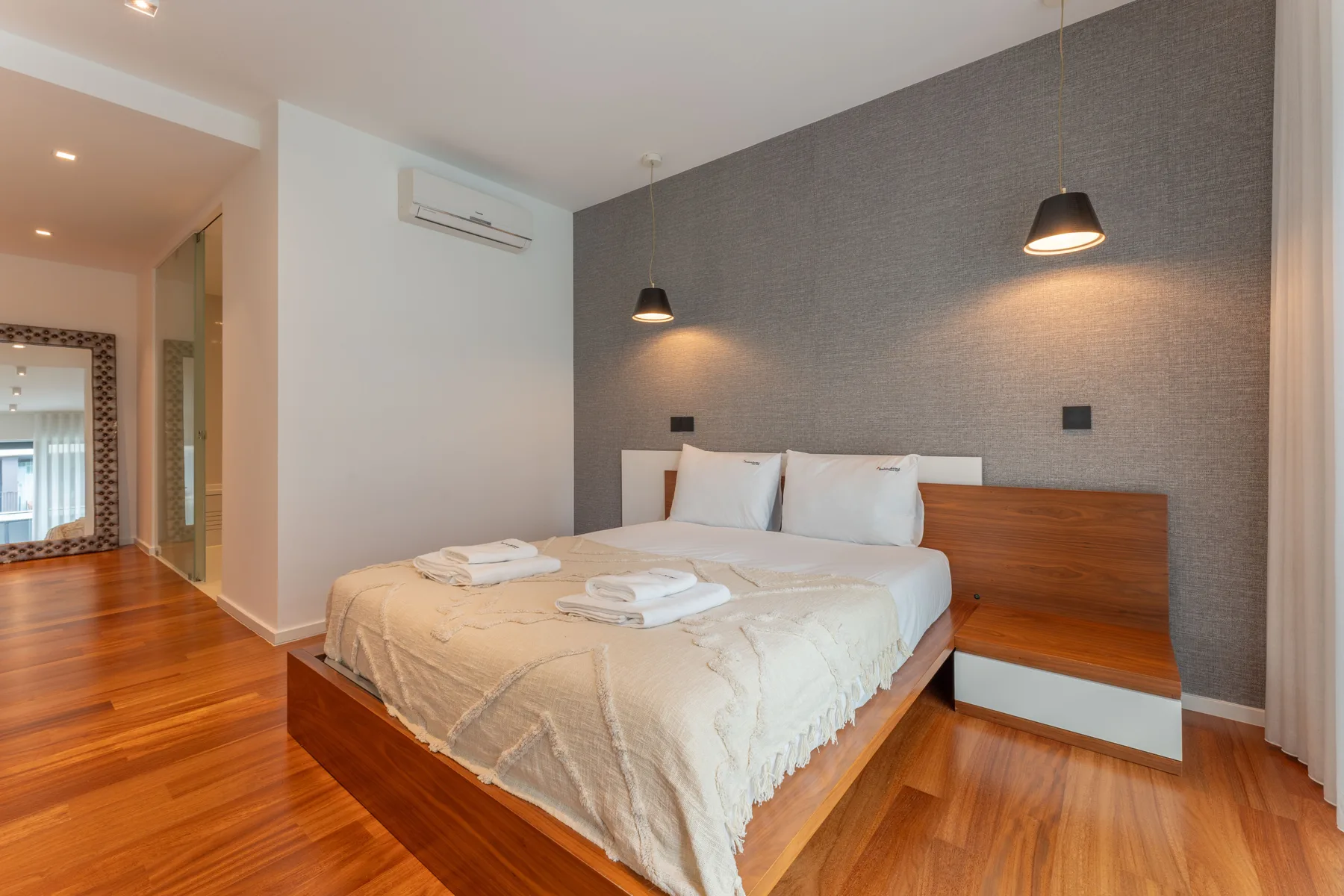 Un dormitorio con una cama, mesitas de noche y suelo de madera cálido.
