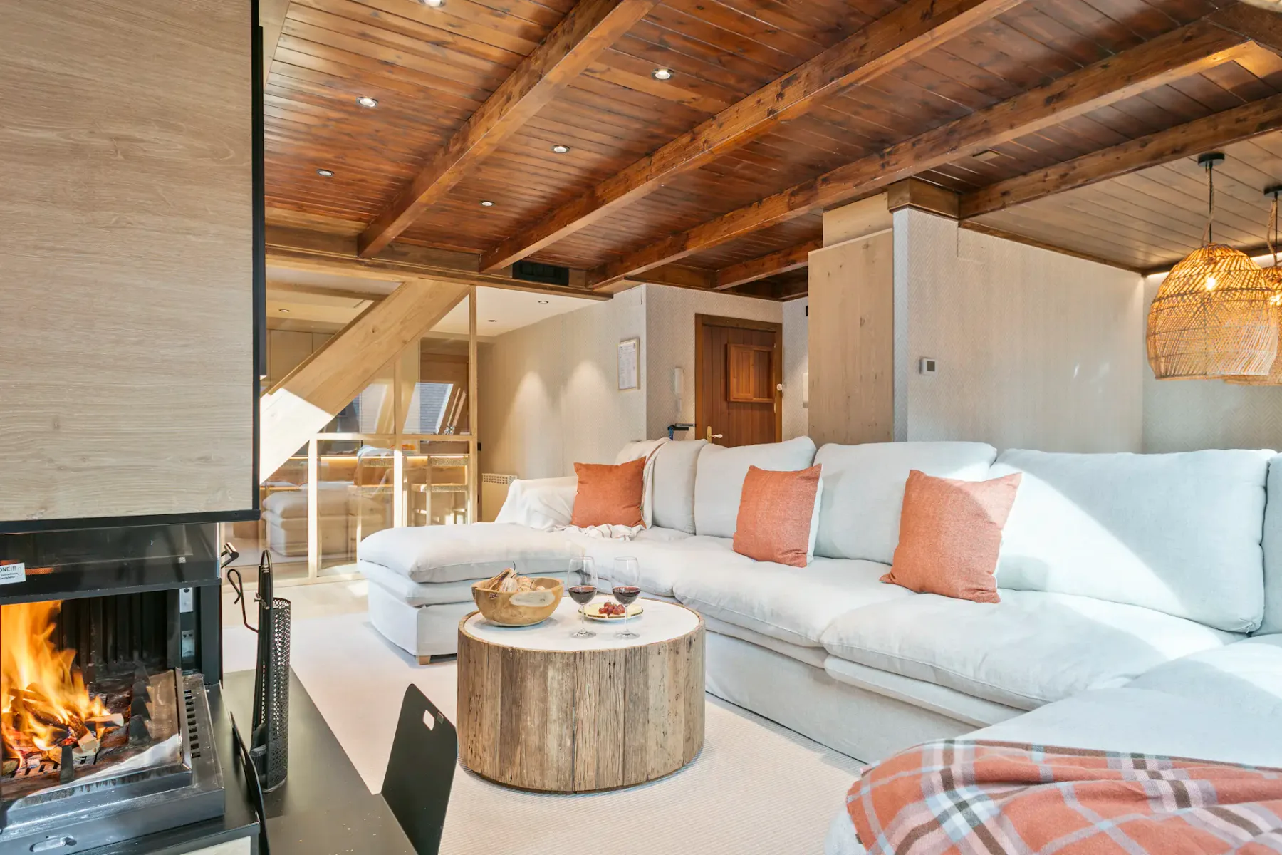 A bright living room with a large white sectional sofa and a round wooden coffee table.