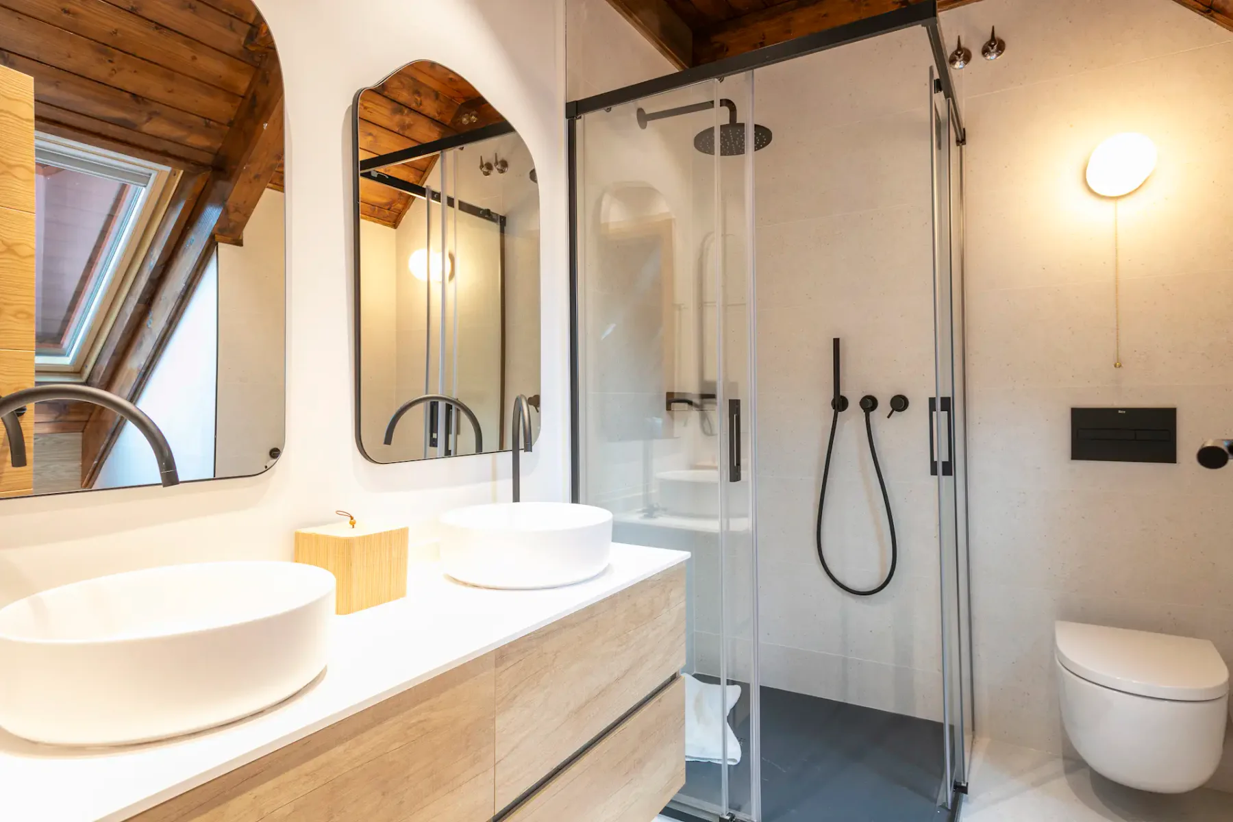Bathroom with a wooden vanity, vessel sinks, and a glass shower enclosure.