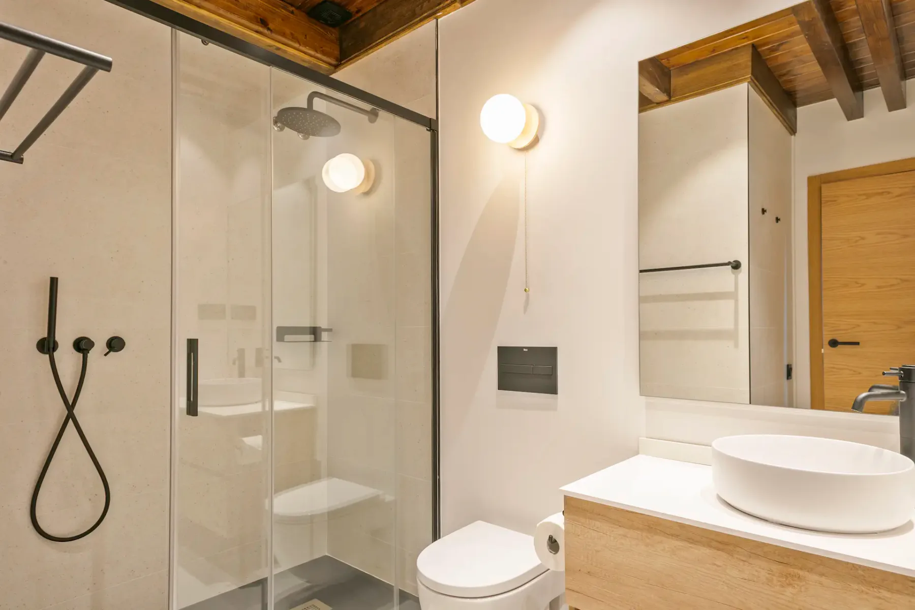 Modern bathroom with a glass shower, a vessel sink, and wood accents.
