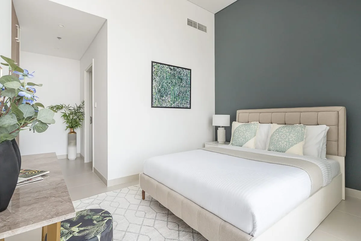 Un dormitorio con una cama bien tendida y una obra enmarcada en la pared.