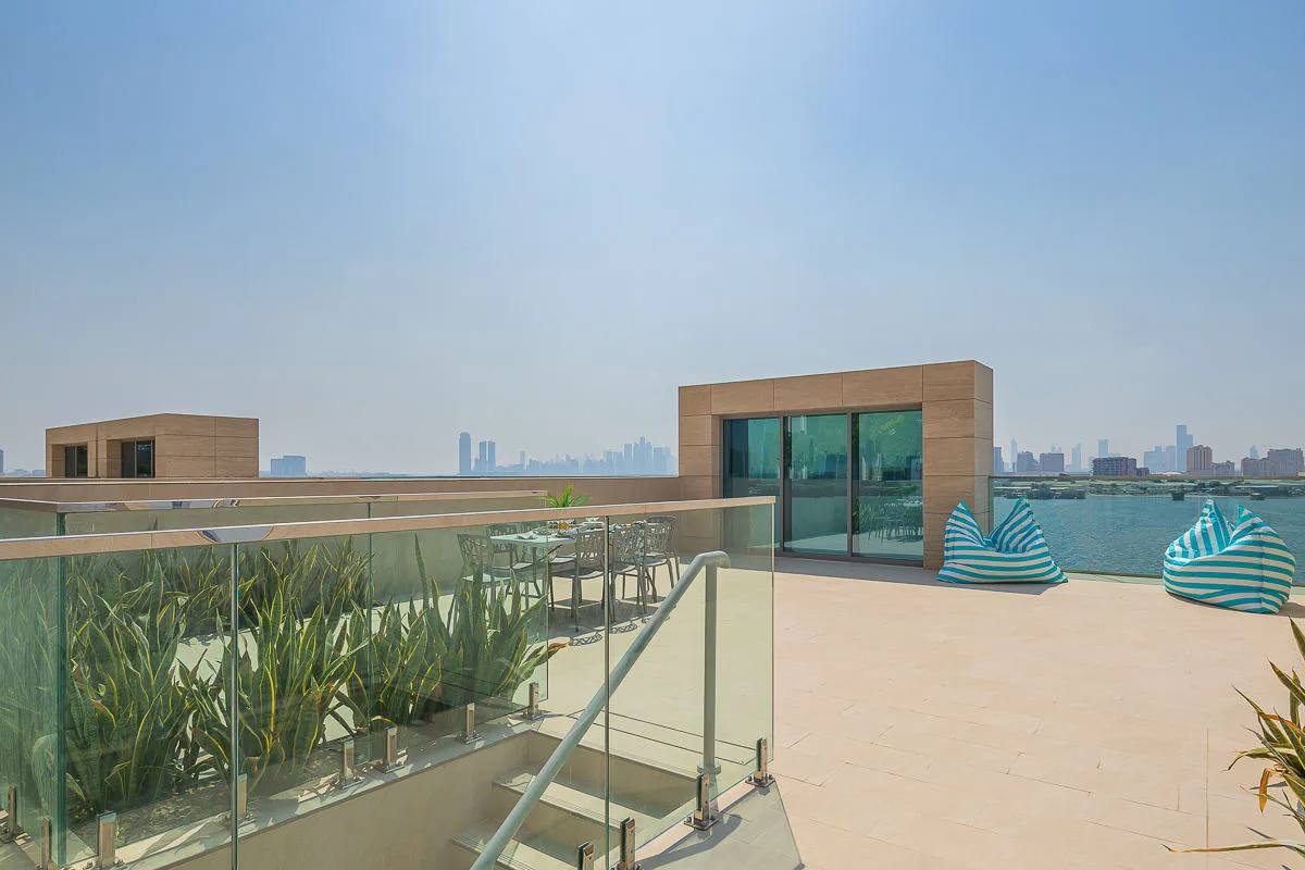 Una terraza en la azotea ofrece vistas de la ciudad, con barandillas de vidrio y asientos al aire libre.