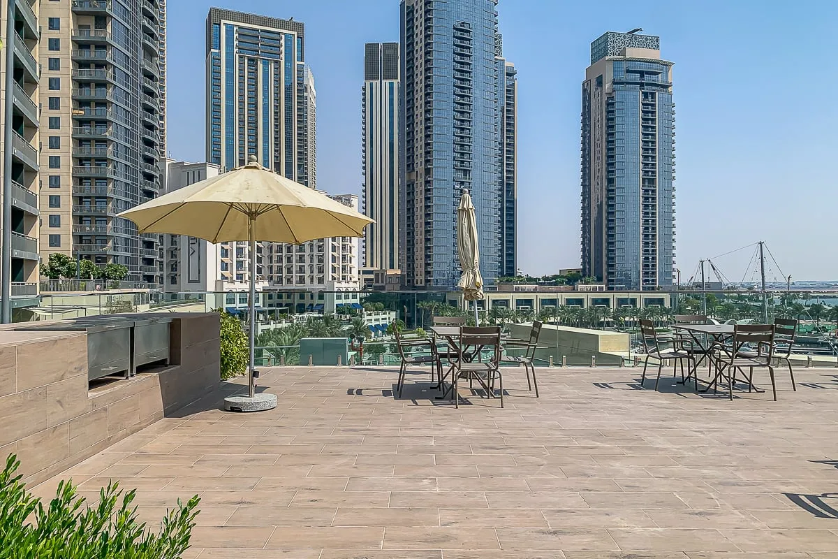 Una terraza al aire libre con mesas y sillas tiene vistas a varios edificios altos.