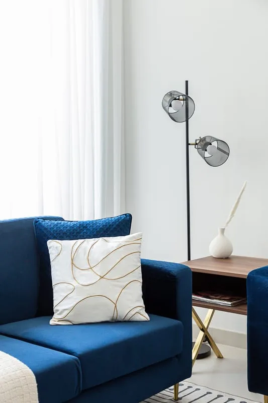 Un espacio de asientos azules con un cojín estampado junto a una mesa auxiliar.